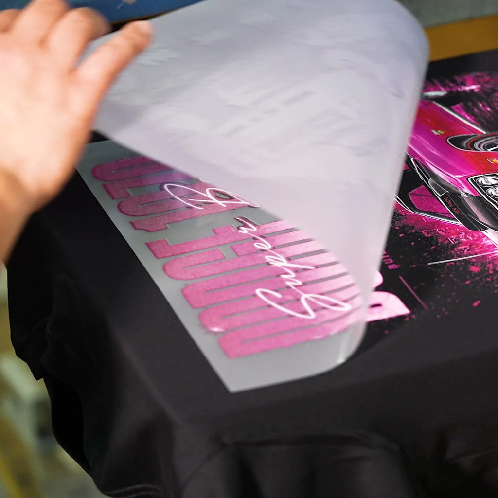 Peeling the carrier away after pressing a transfer onto a black T-shirt