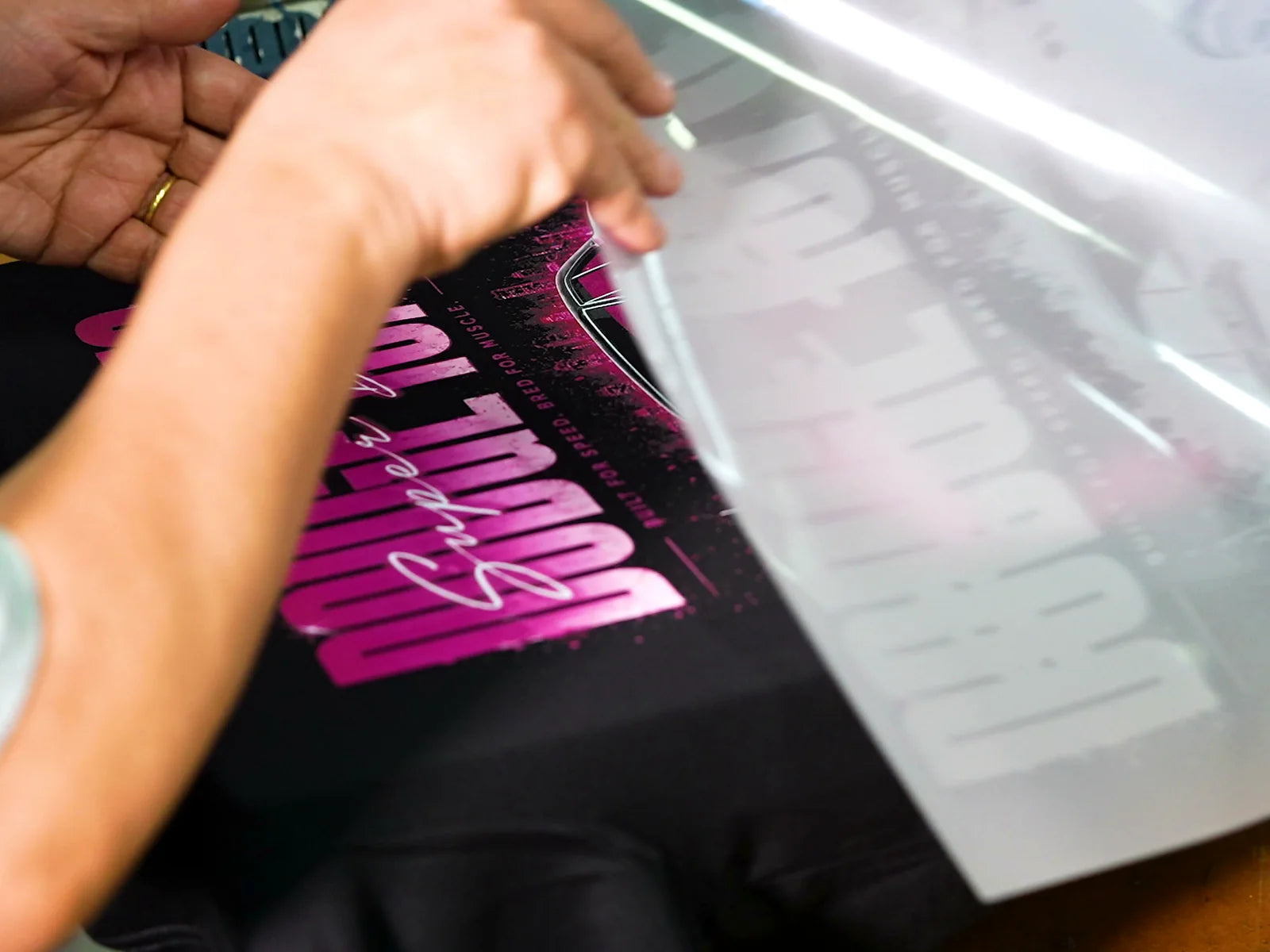Hot-peeling the carrier from a freshly pressed transfer on a black T-shirt